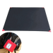 Tapis de camping noir compact avec des coins rouges à côté d'une petite pochette de transport rouge, idéal pour les activités de plein air comme les pique-niques et la randonnée.