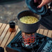 Cuisiner des nouilles sur un réchaud à gaz en inox portable pendant un camping.