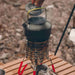 Réchaud à gaz portable en acier inoxydable sur une table en bois, idéal pour le camping en plein air.
