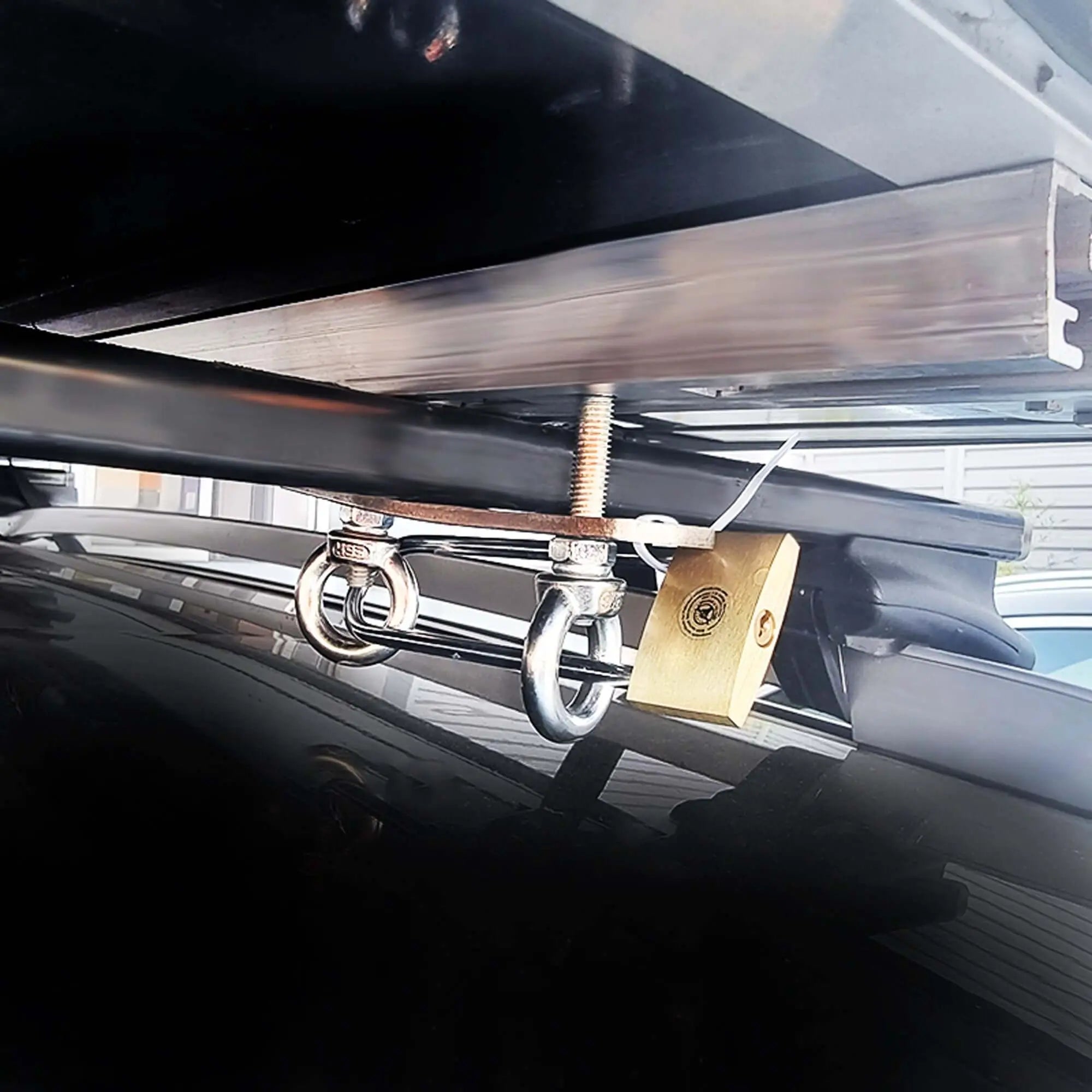 Roof tent anti-theft kit with robust padlock and A4 steel rings secured on car roof rack for enhanced security.
