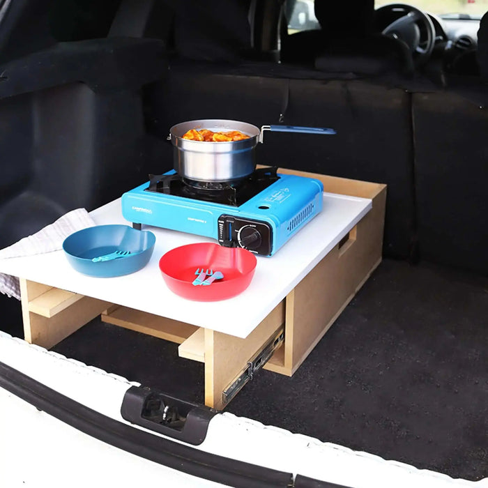 Installation de cuisine de camping portable dans le coffre de la voiture avec réchaud et espace de rangement, parfait pour cuisiner en plein air de manière compacte.
