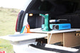 Cuisine de camping dans le coffre de la voiture, montrant un système de rangement en bois compact avec cuisinière et évier, idéal pour transformer les véhicules en mini-fourgonnettes.
