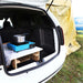 Configuration de camping dans le coffre de la voiture avec un réchaud portable et du rangement, parfait pour transformer votre véhicule en un mini van aménagé.