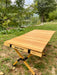 louer materiel camping table chaise montpellier location herault 34000 woodys camp Table de camping en bois pliable installée en extérieur avec des chaises, des boissons et de la nourriture, mettant en avant un design durable pour des repas confortables en plein air.