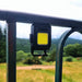 Une mini lampe de poche LED compacte suspendue à une clôture, idéale pour les aventures en plein air, affichant son faisceau lumineux ultrapuissant.