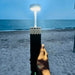Lampe LED télescopique rechargeable et portable illuminant une scène de plage, parfaite pour le camping et les aventures en plein air.