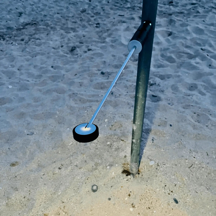 Lampe télescopique LED portable suspendue, en plein air, sur fond de sable, idéale pour le camping et les aventures nocturnes.
