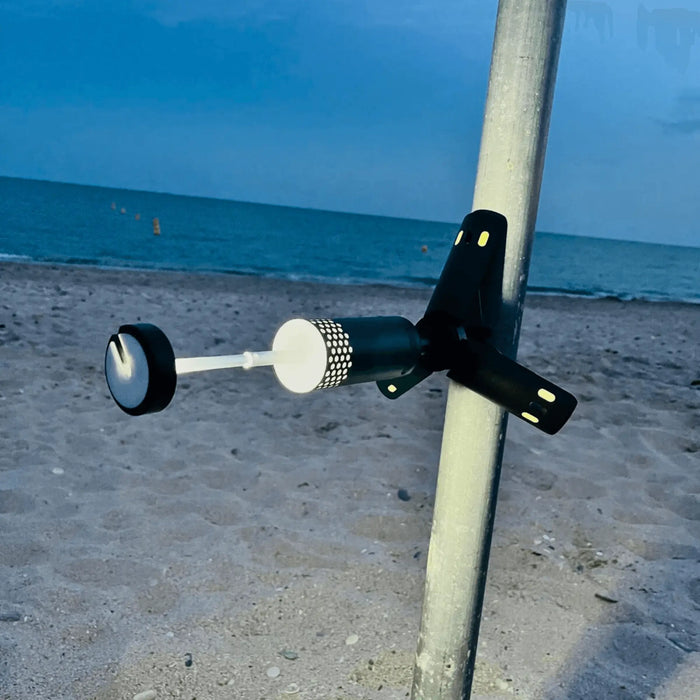 Lampe LED télescopique portable fixée à un mât sur une plage de sable, idéale pour les aventures en plein air comme le camping et les pique-niques nocturnes au bord de la mer.