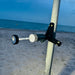 Lampe LED télescopique portable fixée à un mât sur une plage de sable, idéale pour les aventures en plein air comme le camping et les pique-niques nocturnes au bord de la mer.