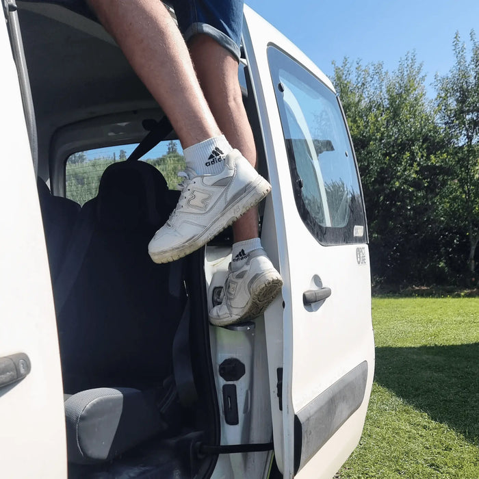 Une personne utilisant une marche de porte de fourgonnette pour un accès facile, illustrant la commodité d'entrée dans une tente de toit.