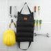 Sac de rangement pliable avec compartiments, accroché, entouré d'outils, sur un fond de panneau perforé.