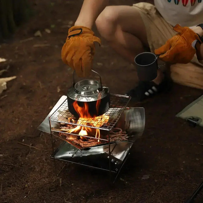 Cuisine en plein air avec un grille-pain en acier inoxydable pliant, mettant en valeur son design compact et sa construction robuste pour les aventures de camping.