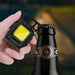 Main tenant une petite lampe de poche LED près d'une bouteille, mettant en valeur son design portable et sa capacité lumineuse puissante.