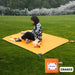 Femme assise sur un mat de camping portable orange dans un parc, idéal pour des pique-niques, des sorties à la plage, des moments de détente dans la nature, des festivals ou des randonnées.