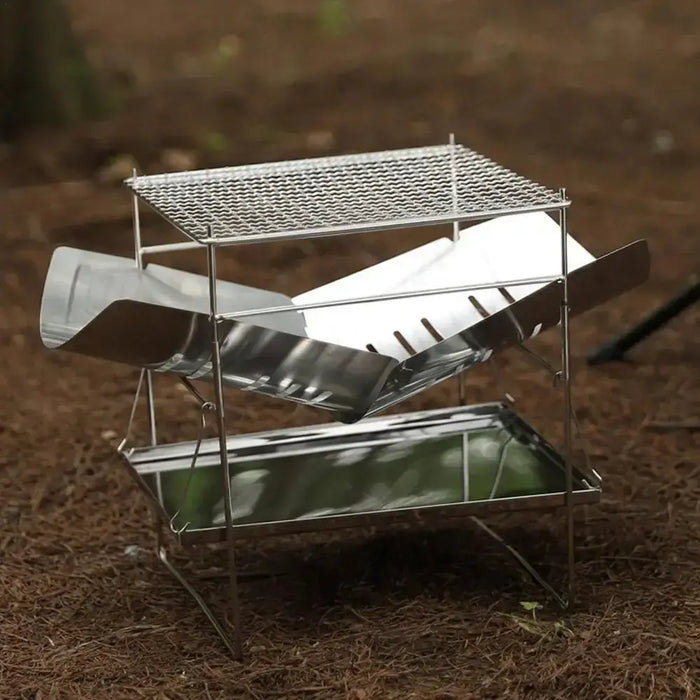 Gril de camping pliant en acier inoxydable, installé en extérieur, mettant en avant son design compact et ses matériaux durables adaptés aux feux de camp.