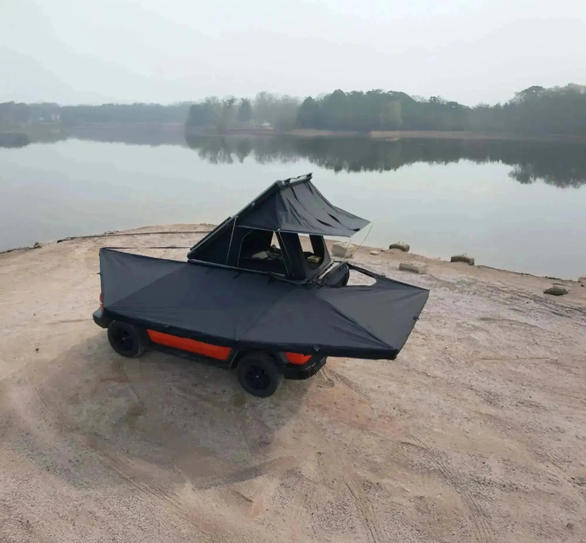 Vehicle equipped with a 360° freestanding awning with integrated LEDs, set up near a lake, showcasing outdoor camping accessories.