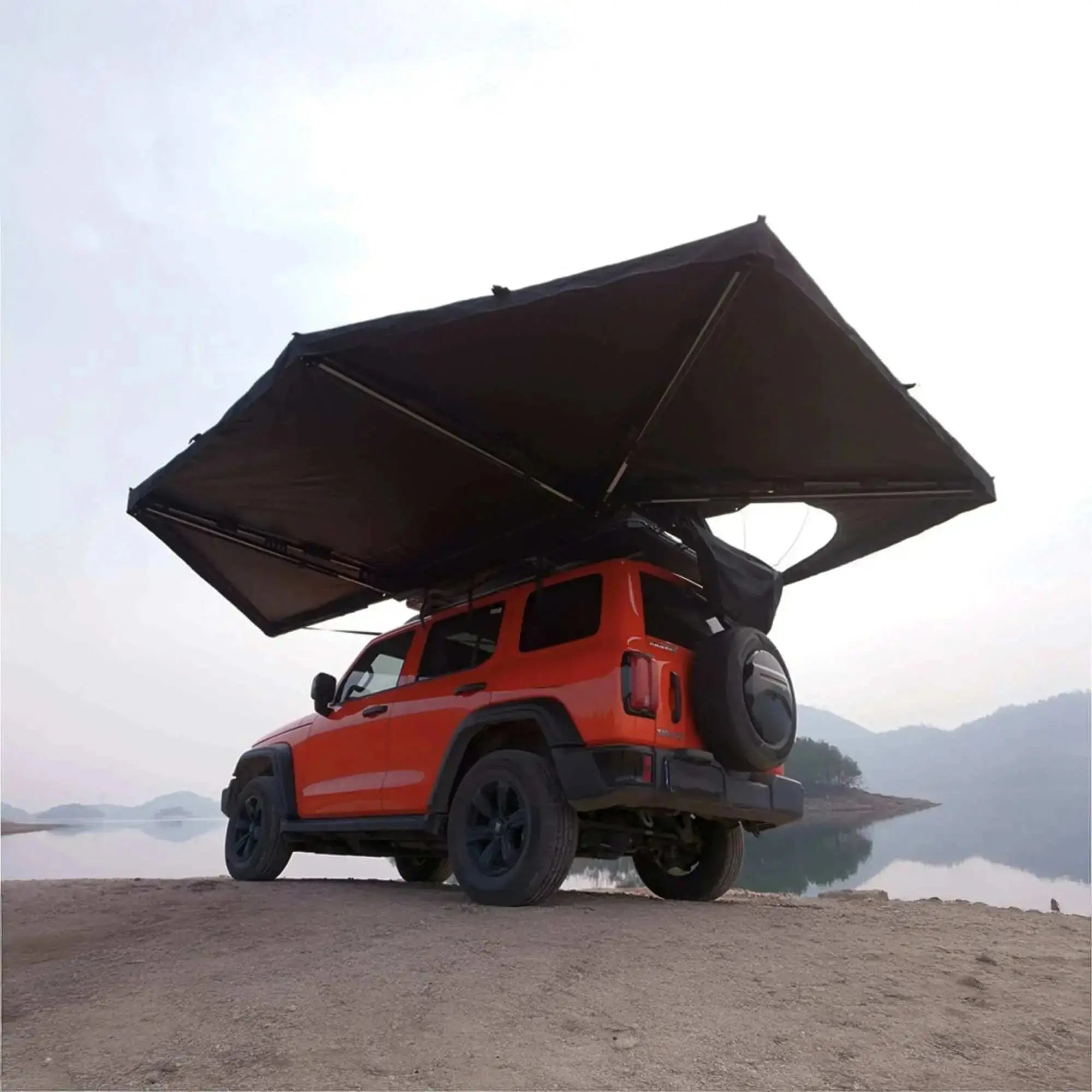 Orange SUV with 360° freestanding awning and integrated LEDs by a lake, showcasing outdoor camping setup.