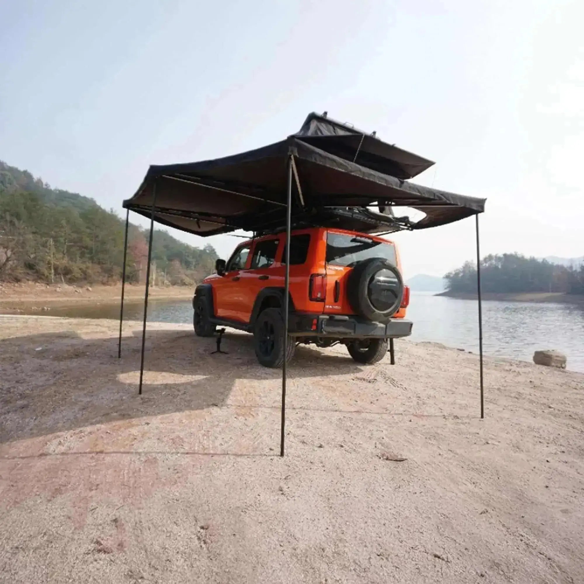 Autoportant 360° awning with LEDs on an off-road vehicle at a lakeside campsite, showcasing coverage and telescopic stability.