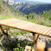 Table pliante en bois pour le camping installée dans un décor montagneux, montrant sa robustesse et sa simplicité de rangement.