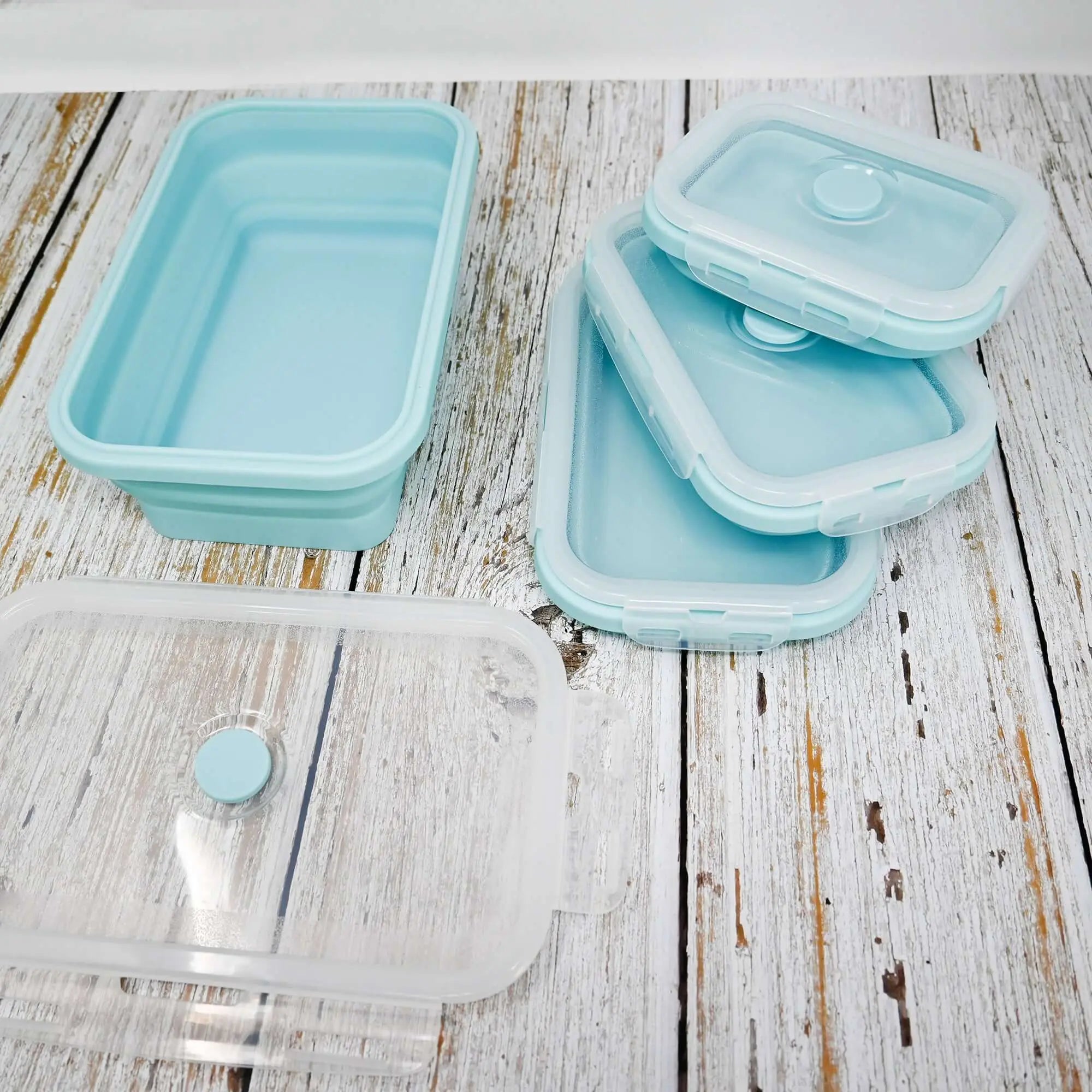 Ensemble de 5 boîtes à lunch en silicone bleu pliables sur une table en bois, idéales pour un stockage peu encombrant, le camping et diverses utilisations.