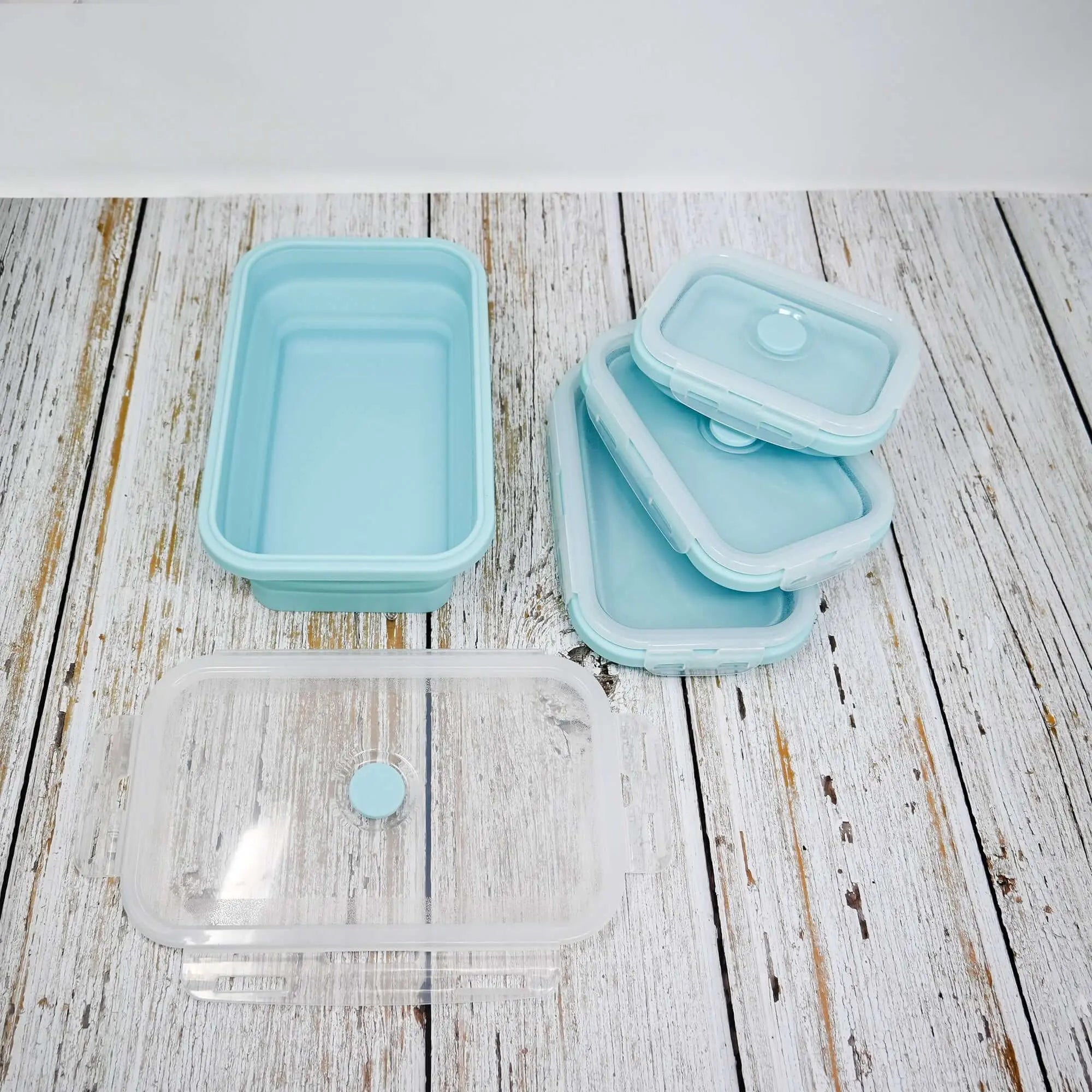 Lot de 5 boîtes à lunch rectangulaires pliables en silicone sur une table en bois.