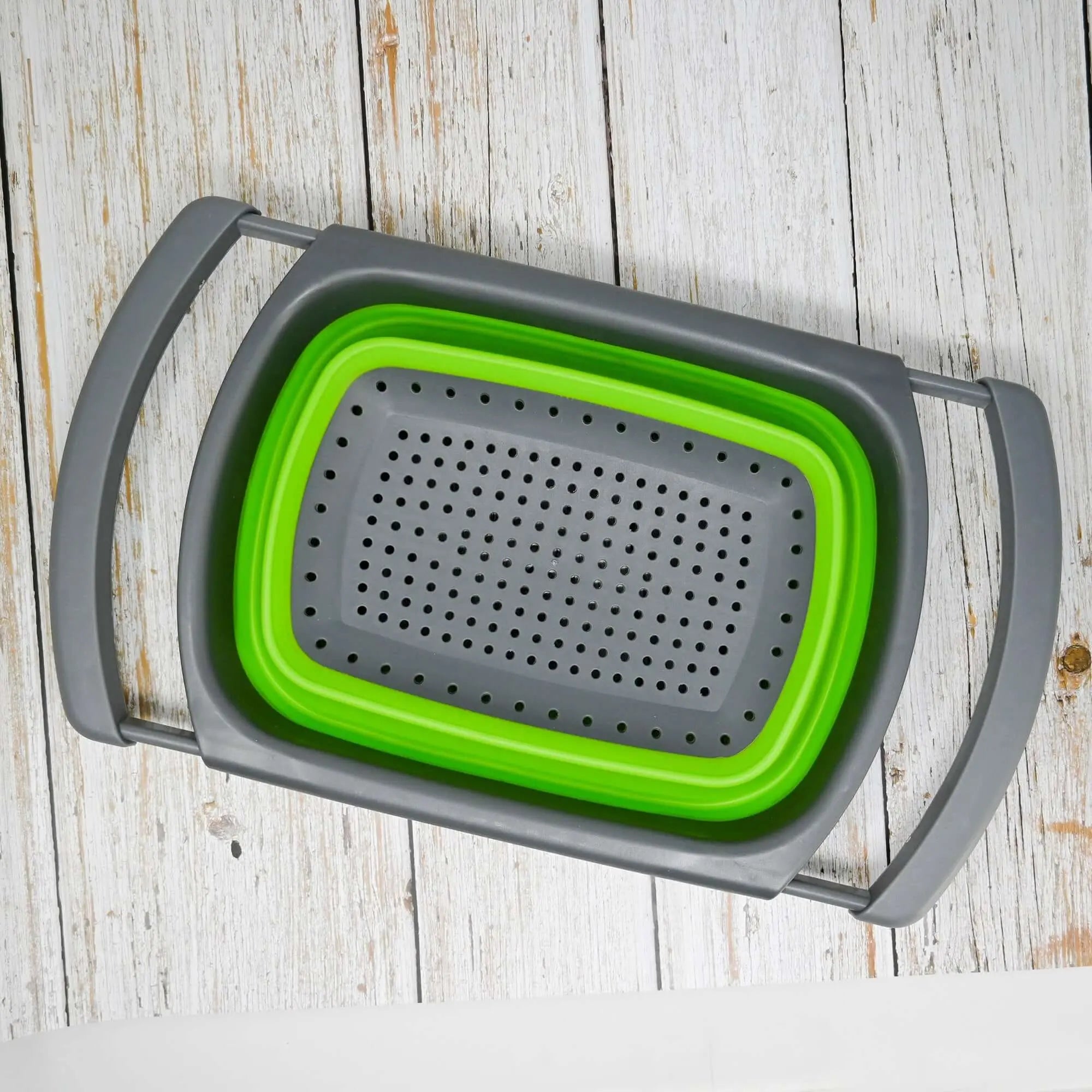 Passoire en silicone pliable avec poignées ajustables, idéale pour le camping et les activités en plein air, sur une surface en bois.