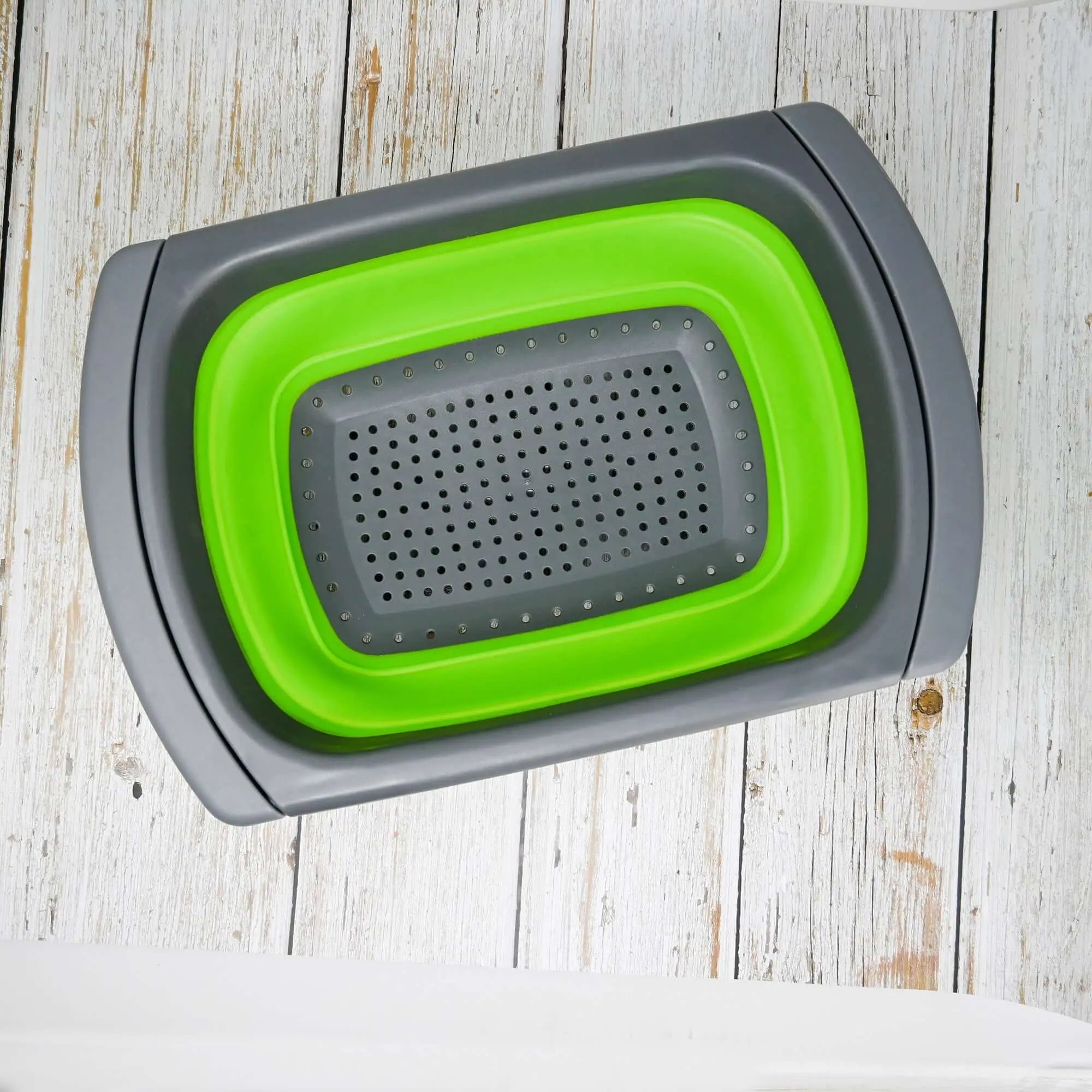 Colander en silicone pliable avec poignées ajustables, idéal pour le camping et les cuisines de plein air, présenté sur une surface en bois rustique.