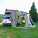 Annexe de tente de toit rigide avec plusieurs ouvertures, attachée à une voiture, offrant un espace de vie supplémentaire pour le camping.