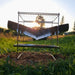 Ensemble de grill en acier inoxydable pliable installé dans un champ herbeux au coucher du soleil, parfait pour le camping portable et la cuisine en plein air.