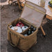 Boîte de transport pliable avec armature métallique contenant de l'équipement de camping sur une table en bois, idéale pour le rangement et le transport.