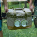 Boîte de transport pliable avec armature métallique, idéale pour le camping, portée par deux personnes, montrant sa robustesse.