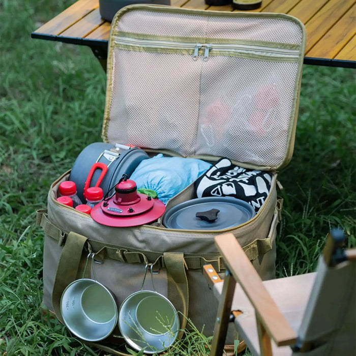 Boîte de transport pliable avec équipements de camping, armature métallique visible, posée sur herbe verte.