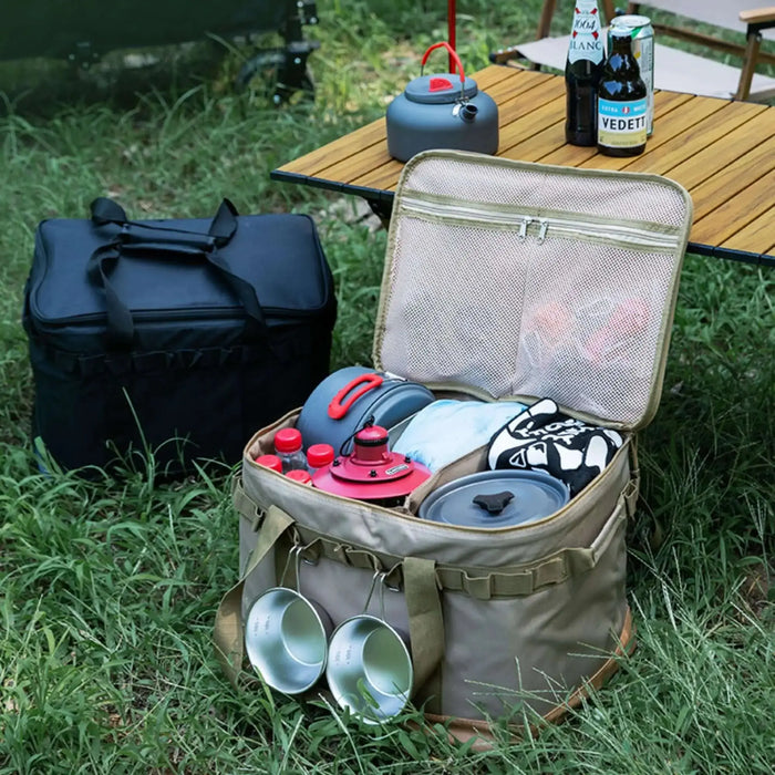 Boîte de transport pliable avec armature métallique remplie d'équipements de camping, posée sur l'herbe pour une sortie en plein air.