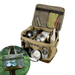 Boîte de transport pliable pour le camping avec armature métallique, remplie d'équipements divers et tasse accrochée, sur fond d'herbe.