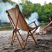 Chaise pliante en bois XL beige au bord de la rivière, idéale pour le camping et la détente en plein air.