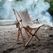 Chaise pliante en bois XL beige sur une plage, idéale pour le camping, les pique-niques et la détente, fabriquée en bois massif et tissu résistant.