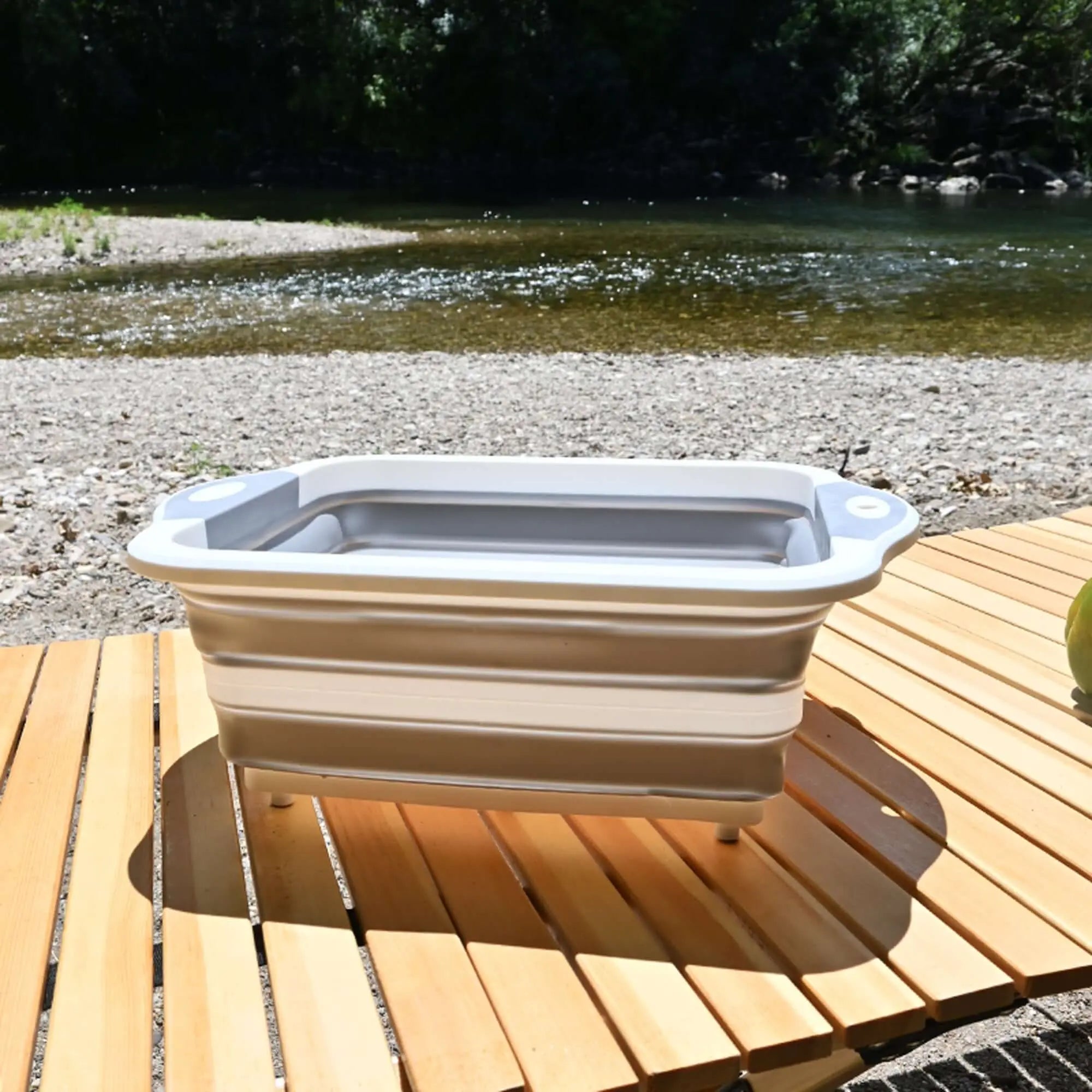Évier pliable en silicone posé sur une table de camping en plein air, idéal pour la cuisine mobile