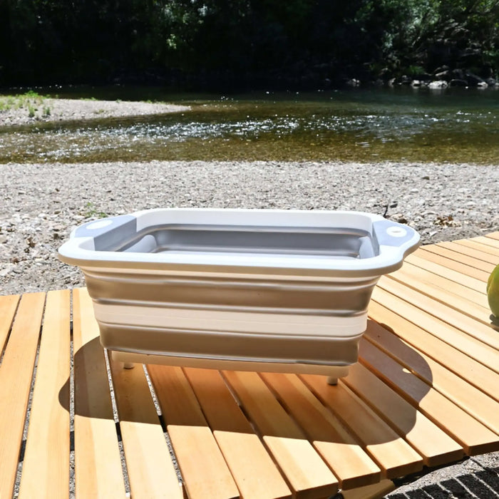 Évier pliable en silicone posé sur une table de camping en plein air, idéal pour la cuisine mobile.