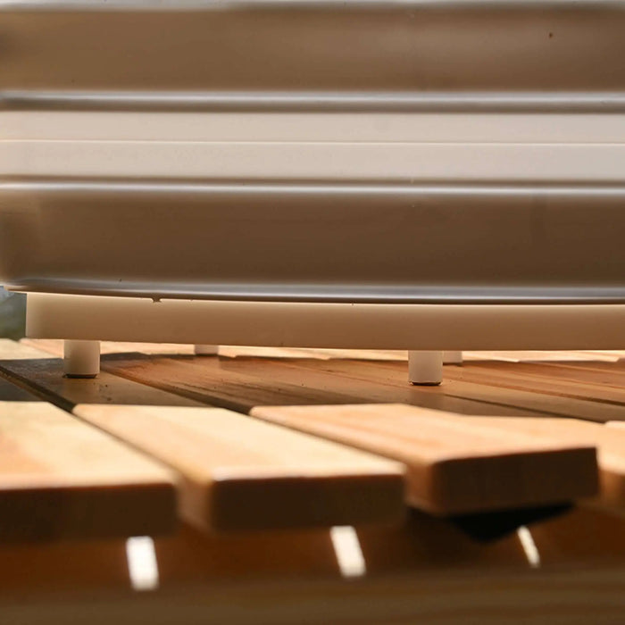 Gros plan d'un évier de camping en silicone pliable et d'une planche à découper, sur une surface en bois à l'extérieur.