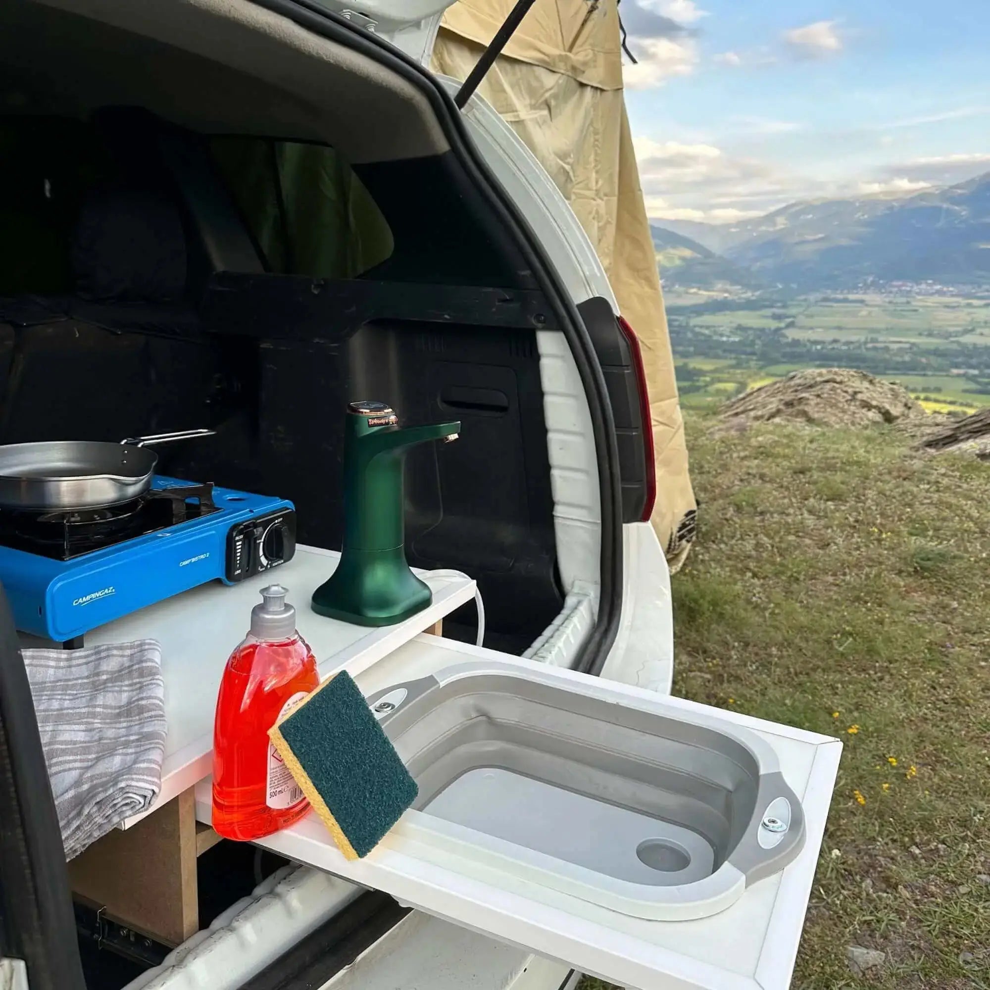 Évier pliable en silicone pour camping installé dans un van avec vue sur les montagnes, idéal pour la cuisine en plein air.