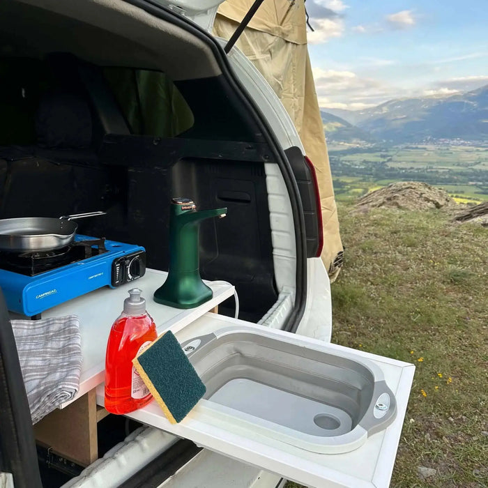 Évier pliable en silicone pour camping installé dans un van avec vue sur les montagnes, idéal pour la cuisine en plein air.