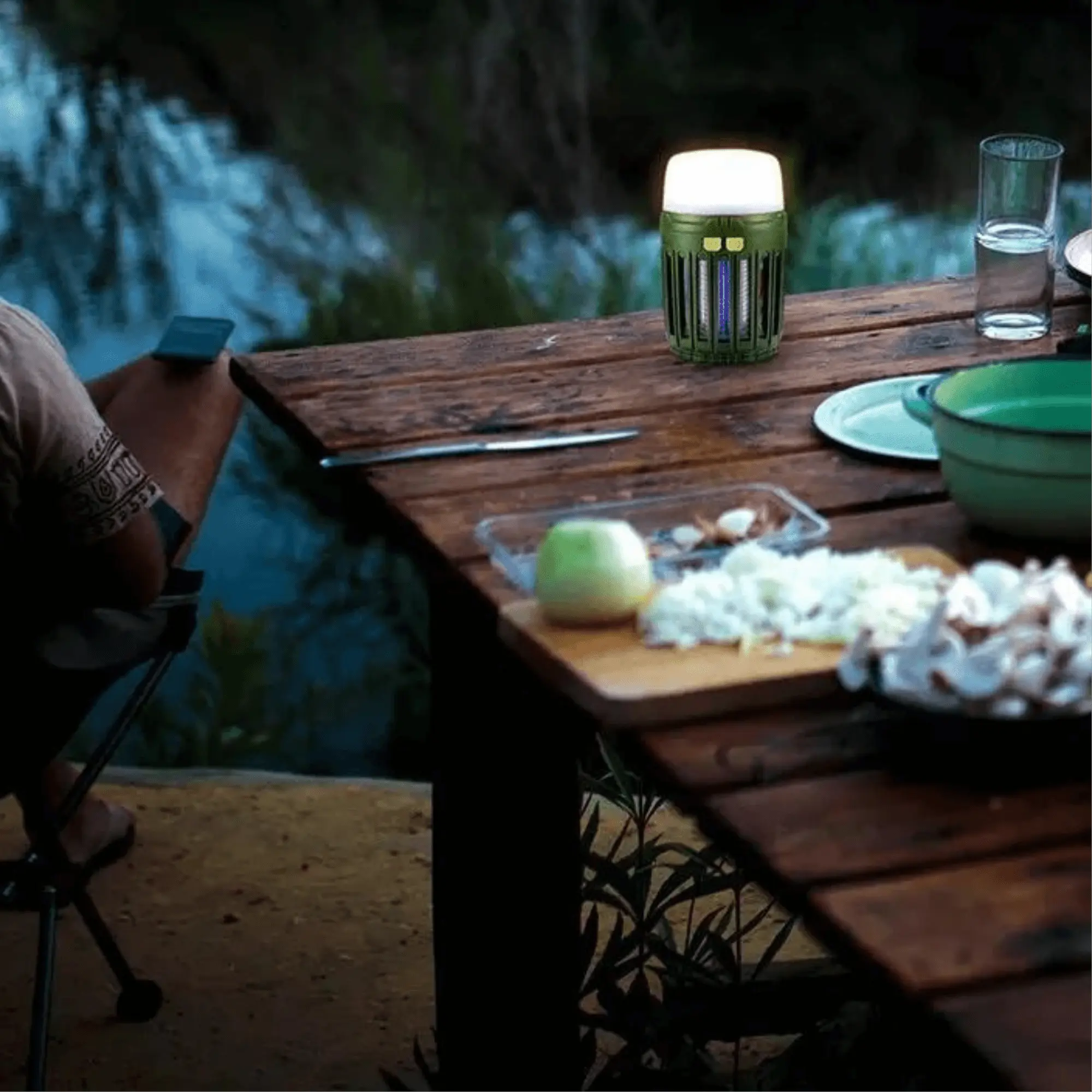 Lampe anti-moustique multifonction éclairant une table de camping au bord de l'eau, idéale pour protéger vos soirées en plein air.