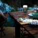 Lampe anti-moustique multifonction éclairant une table de camping au bord de l'eau, idéale pour protéger vos soirées en plein air.