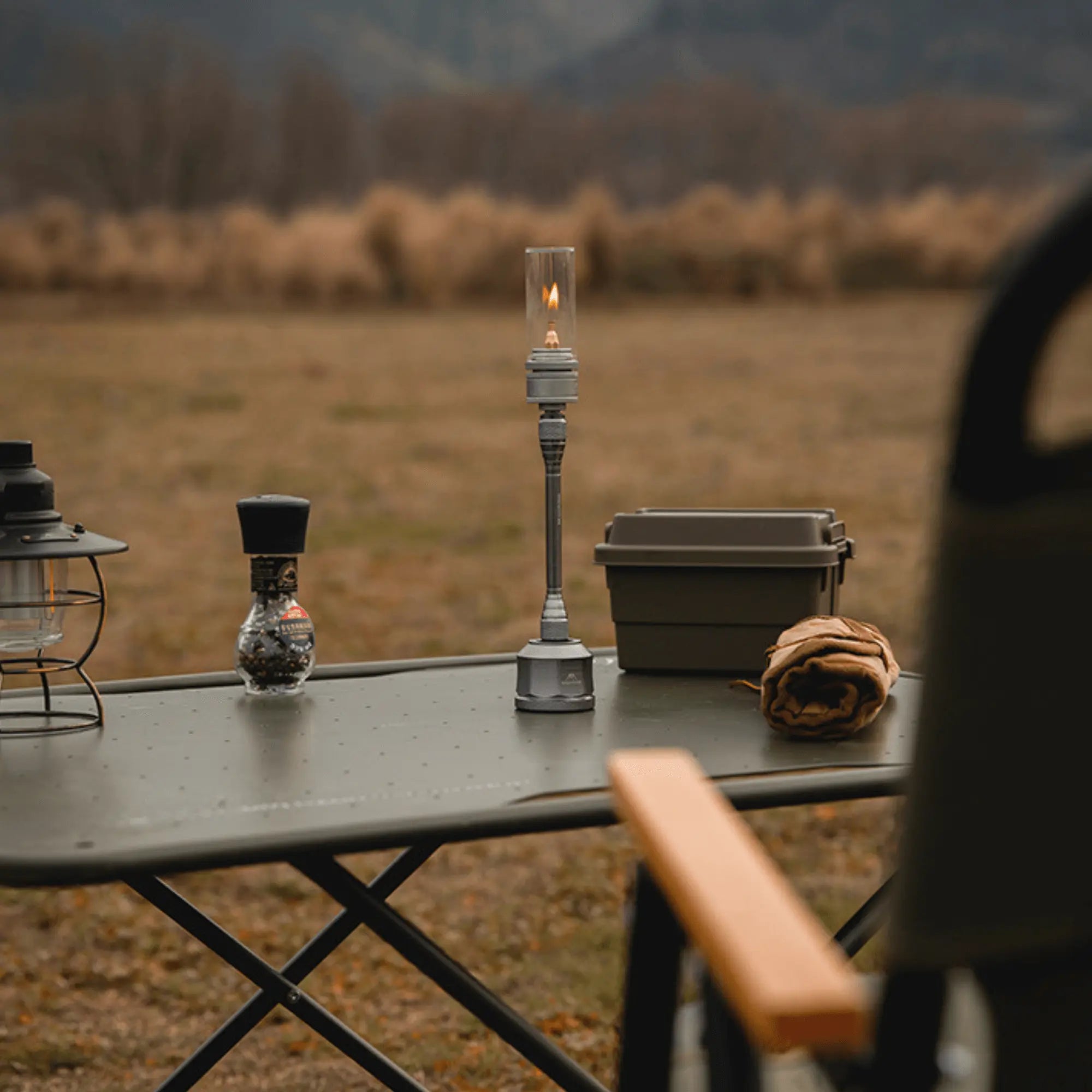 Camping table setup with a rechargeable gas lantern, perfect for creating a warm atmosphere outdoors, surrounded by scenic nature view.