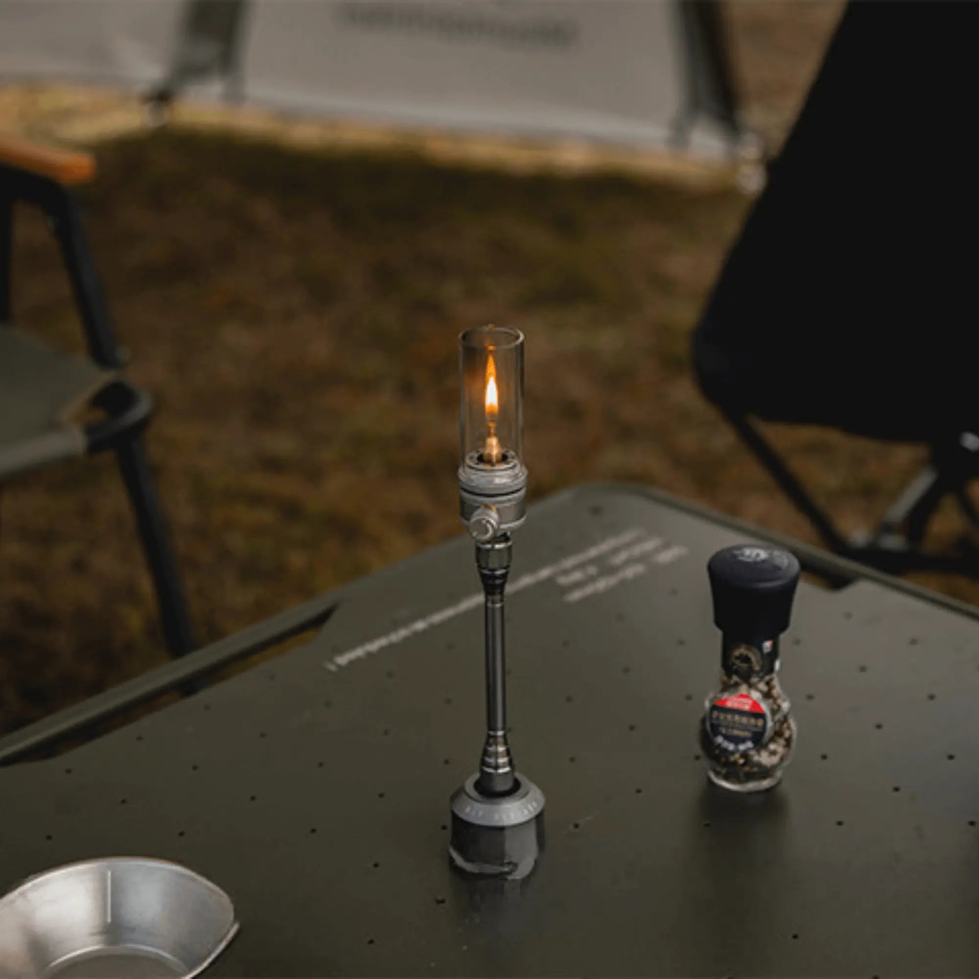 Lampe lanterne à gaz de camping rechargeable sur table en plein air, offrant un éclairage chaleureux pour soirées nature.