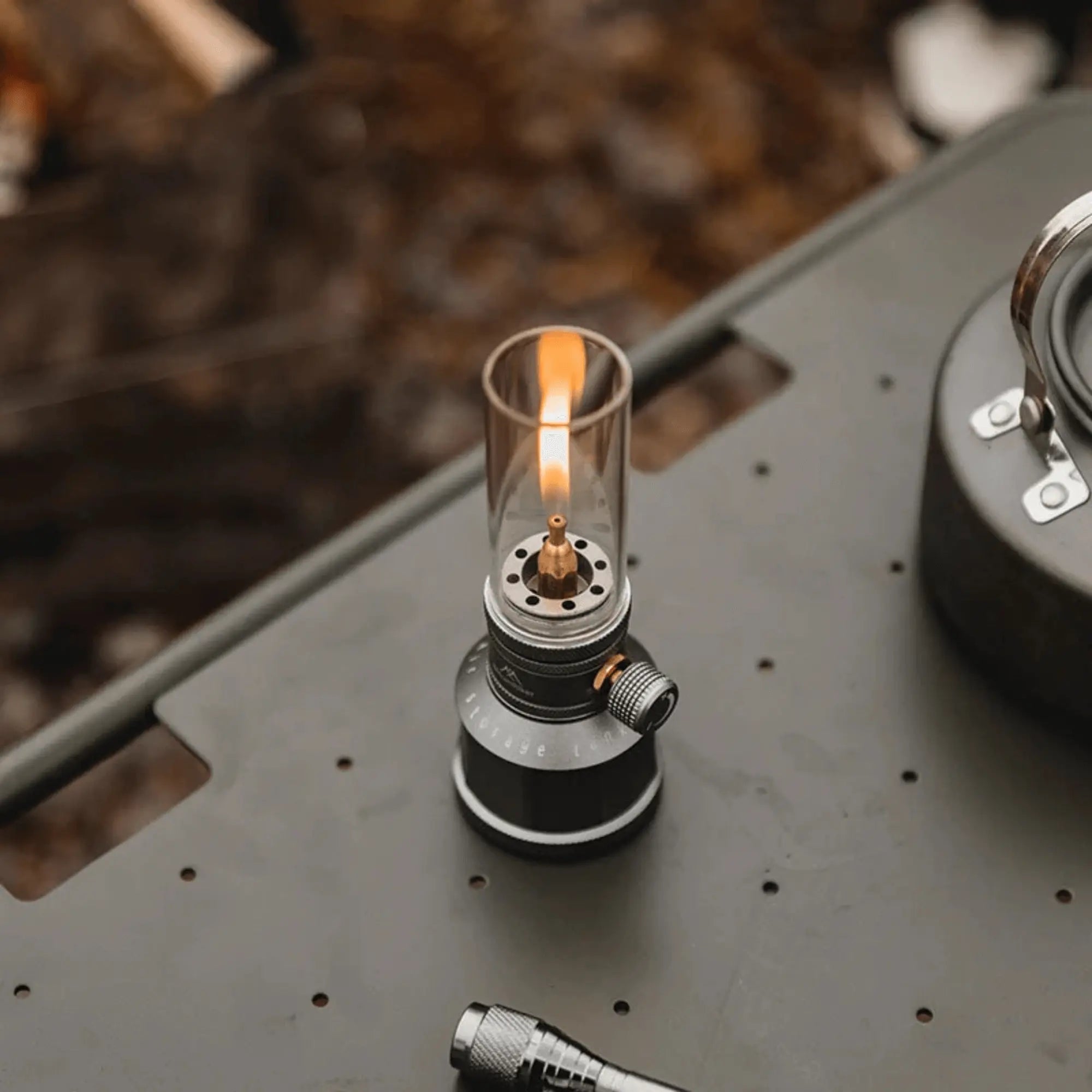 Rechargeable camping gas lantern on outdoor table, providing warm light for evening adventures.