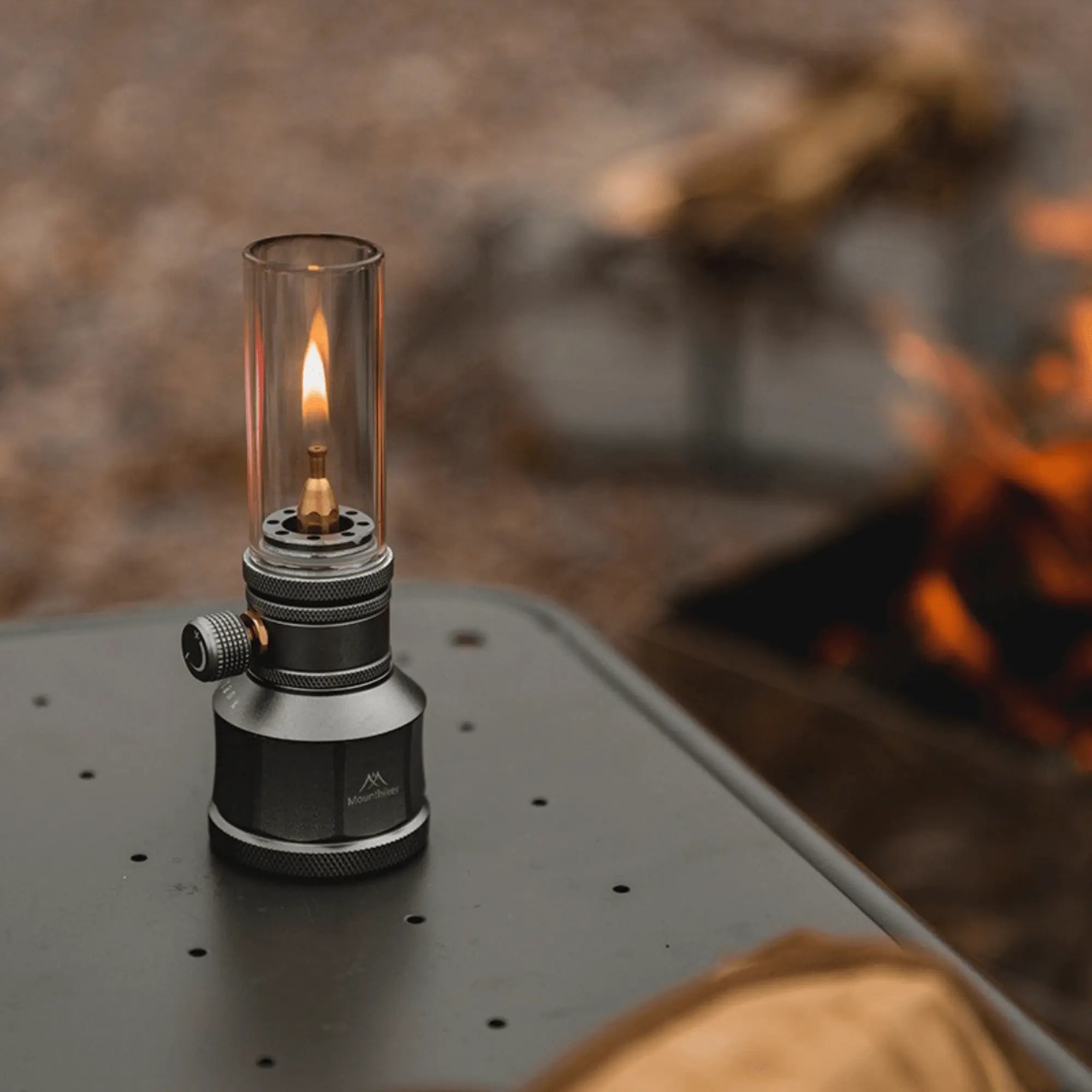 Rechargeable gas camping lantern on table, emitting warm light, perfect for outdoor adventures like camping and hiking.