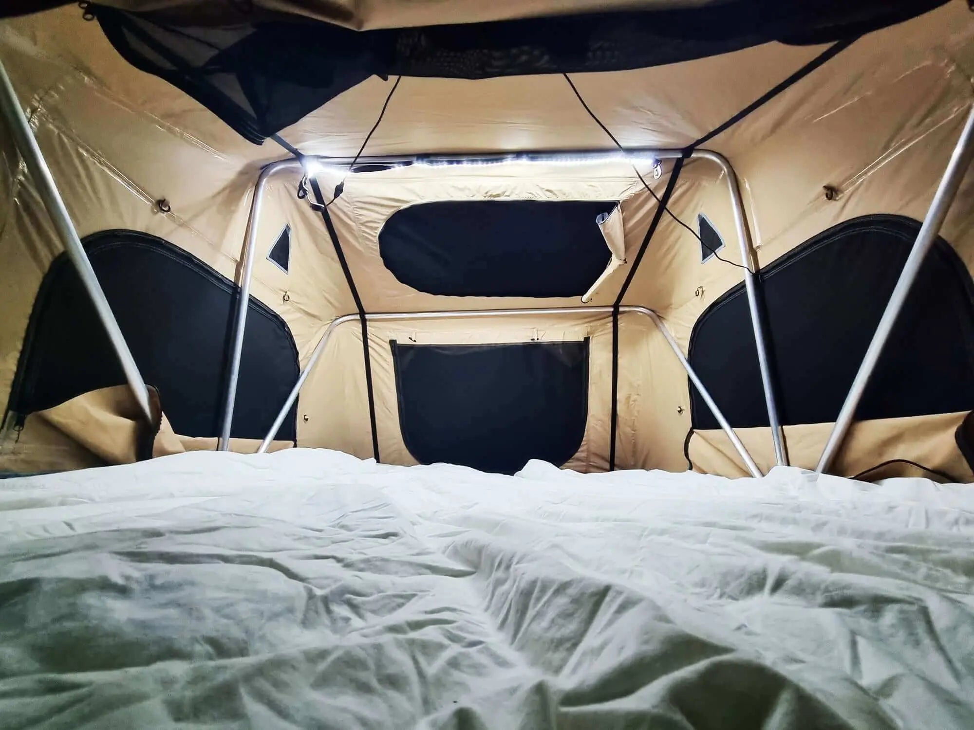Interior of a rooftop tent with flexible LED strip lighting for camping, highlighting portability and illumination.