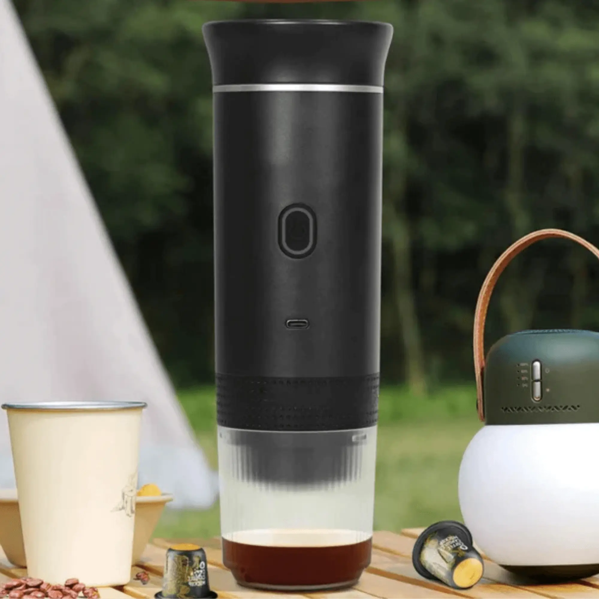 Portable electric coffee maker, perfect for making espresso while camping or traveling, shown on a picnic table.