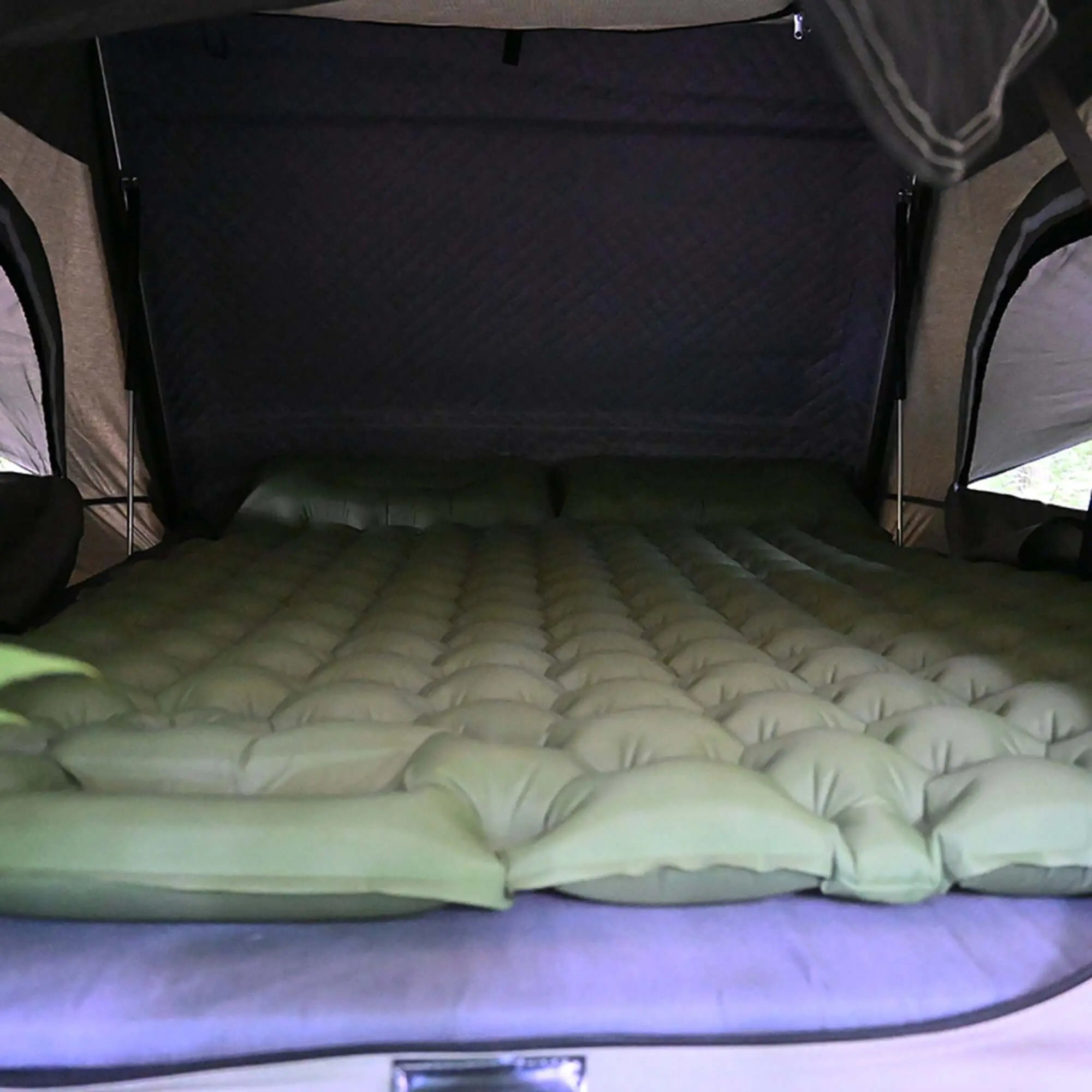 Inflatable camping mattress in rooftop tent for comfortable outdoor sleep, fits 1-2 people.